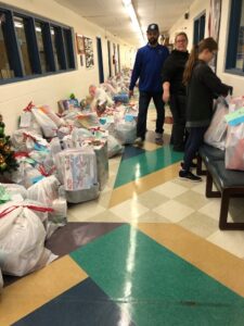 Tons of gifts all wrapped up in bags all down a hallway ready for pick up from the families.